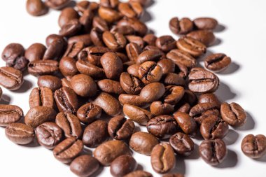 Beyaz arkaplanda paket tasarımı elementleri olarak izole edilmiş taze kahve çekirdekleri yığını.