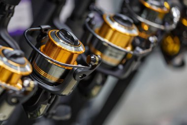 Balıkçı dükkanının tezgahında farklı boyutlarda bobinli oltalar var.