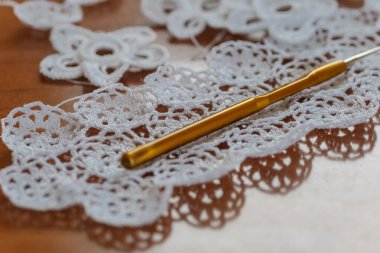 Örgü örüyorum. Bir tutam çiçek. Arka plan olarak el yapımı İrlanda danteli