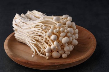 Siyah arkaplan üzerinde Enoki mantarları. Enokitake veya enoki (Flammulina velutipes) beyaz mantar i yemek ve salata kullanılır, ayrıca altın iğne mantarı veya zambak mantarı olarak da bilinir..