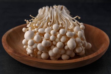 Siyah arkaplan üzerinde Enoki mantarları. Enokitake veya enoki (Flammulina velutipes) beyaz mantar i yemek ve salata kullanılır, ayrıca altın iğne mantarı veya zambak mantarı olarak da bilinir..