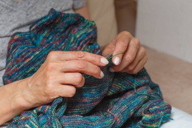 Yün ipliği kullanarak telli el yapımı giysiler ören tanınmamış bir kadının ellerine yakın durun. Boş zaman etkinliği kavramı. İplikten örgü örmek..