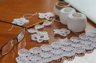 Örgü örüyorum. Bir tutam çiçek. Arka plan olarak el yapımı İrlanda danteli