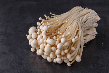 Taze Enoki mantarları seçilmiş odaklı olarak siyah zemin üzerinde bulunur. Enoki, ayrıca kadife şiş olarak da bilinir, Physalacriaceae familyasından yenilebilir bir mantar türüdür.. 