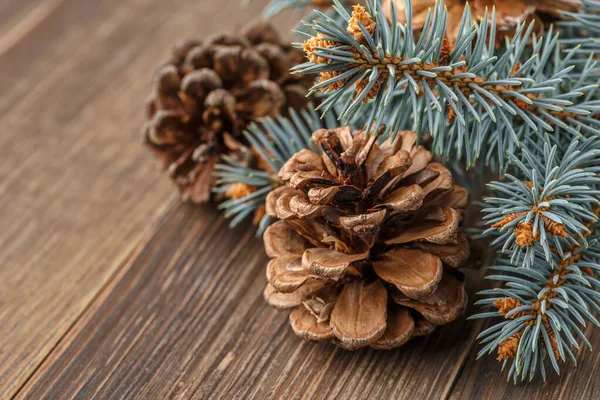Çam kozalağı ve yeşil dal ahşap masada. Noel kartı. Ahşap arka planda çam kozalakları.