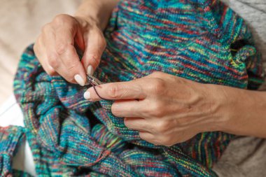 Yün ipliği kullanarak telli el yapımı giysiler ören tanınmamış bir kadının ellerine yakın durun. Boş zaman etkinliği kavramı. İplikten örgü örmek..