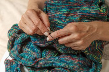 Yün ipliği kullanarak telli el yapımı giysiler ören tanınmamış bir kadının ellerine yakın durun. Boş zaman etkinliği kavramı. İplikten örgü örmek..