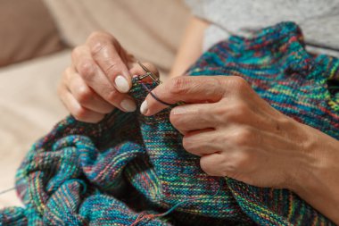 Yün ipliği kullanarak telli el yapımı giysiler ören tanınmamış bir kadının ellerine yakın durun. Boş zaman etkinliği kavramı. İplikten örgü örmek..