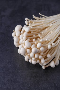 Taze Enoki mantarları seçilmiş odaklı olarak siyah zemin üzerinde bulunur. Enoki, ayrıca kadife şiş olarak da bilinir, Physalacriaceae familyasından yenilebilir bir mantar türüdür.. 