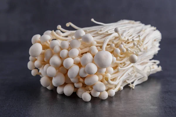 Fresh Enoki mushrooms on black background with selected focus.Enoki, also known as velvet shank, is a species of edible mushroom in the family Physalacriaceae.