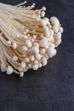 Taze Enoki mantarları seçilmiş odaklı olarak siyah zemin üzerinde bulunur. Enoki, ayrıca kadife şiş olarak da bilinir, Physalacriaceae familyasından yenilebilir bir mantar türüdür.. 