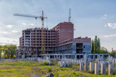 İnşaat halindeki yüksek bina, iskeleli vinç, bir inşaat alanında Freestanding kulesi. Mavi gökyüzüne karşı inşaat alanı çalışması.