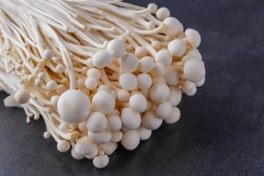 Taze Enoki mantarları seçilmiş odaklı olarak siyah zemin üzerinde bulunur. Enoki, ayrıca kadife şiş olarak da bilinir, Physalacriaceae familyasından yenilebilir bir mantar türüdür.. 