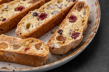 İtalyan bademli bisküvileri kırsal bir evde yapılmış çömlek kasesinde. Badem ve yaban mersiniyle süslenmiş bu iki kez pişirilmiş ikramlar aromatik ve davetkar. İdeal.