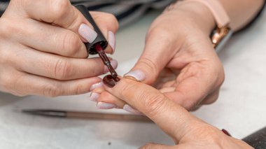 Güzellik salonunda çivi bakım prosedürü. Kadın eli ve manikür aletleri, güzellik salonunda manikür yapma süreci. Spa vücut bakımı kavramı. Tırnak etlerini kesen yetenekli bir manikürcünün eldivenli elleri.