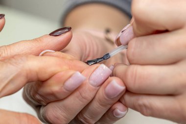 Güzellik salonunda çivi bakım prosedürü. Kadın eli ve manikür aletleri, güzellik salonunda manikür yapma süreci. Spa vücut bakımı kavramı. Tırnak etlerini kesen yetenekli bir manikürcünün eldivenli elleri.