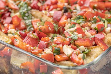 Akdeniz usulü kavrulmuş sebzeler, beyaz rustik bir masada, malzemelerle birlikte salata kasesinde. Beyaz arka planda kapari ve zeytinlerle kızartılmış sarı ve kırmızı biber salatası. Izgara sebze..