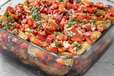 Akdeniz usulü kavrulmuş sebzeler, beyaz rustik bir masada, malzemelerle birlikte salata kasesinde. Beyaz arka planda kapari ve zeytinlerle kızartılmış sarı ve kırmızı biber salatası. Izgara sebze..