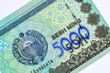 5000 Özbek banknotu. Ters tarafta Taşkent 'teki parlamento binası, ters tarafta ise Özbekistan Cumhuriyeti' nin ulusal amblemi yer alıyor..