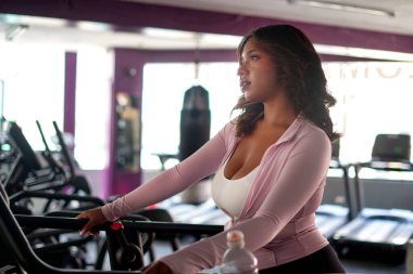 Spor salonundaki koşu bandında kardiyo çalışması yapan bir kadın spor salonuna ve sağlıklı bir yaşam tarzına odaklanıyor. Fiziksel sağlığını korurken aktif giysi giyiyor.