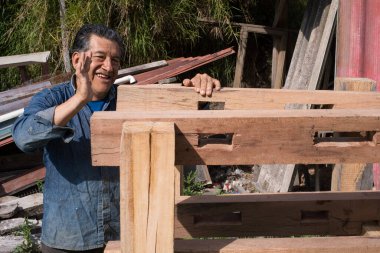 Deneyimli marangoz el yapımı ahşap çerçeve doğramacılığını gururla sergiliyor, ahşap kirişleri geleneksel ahşap işçiliği teknikleriyle bir açık hava atölyesinde birleştiriyor