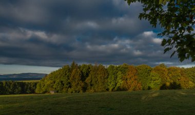 Gündoğumu Ceske Budejovice şehri yakınlarında sonbahar renklerinde güneşli bir sabah yeşil ormanla