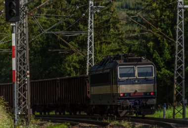 Yazın güneşli sabahlarda Vysoke Tatry dağlarının altında mavi elektrikli kargo treni
