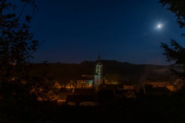 Kasaba koyu renk sonbahar gecesinde tepenin üstünde kiliseyle