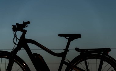 Güneş doğarken siyah ve gri elektrikli bisiklet. Buz gibi arazide sabah vakti. Sarı güneşli.