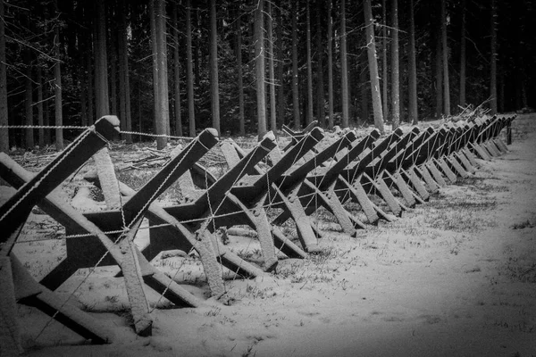 Old border barrier in snowy forest black and white view