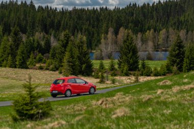 Kırmızı hızlı araba ilkbaharda gün doğumu ormanında ıslak siyah yolda sabah yağmuru