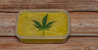 Ahşap masa üzerinde marihuana yağı zencefilli ekmek ve yeşil yapraklar.