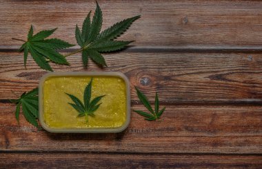 Ahşap masa üzerinde marihuana yağı zencefilli ekmek ve yeşil yapraklar.