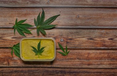 Ahşap masa üzerinde marihuana yağı zencefilli ekmek ve yeşil yapraklar.