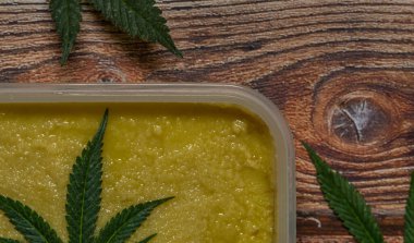 Ahşap masa üzerinde marihuana yağı zencefilli ekmek ve yeşil yapraklar.