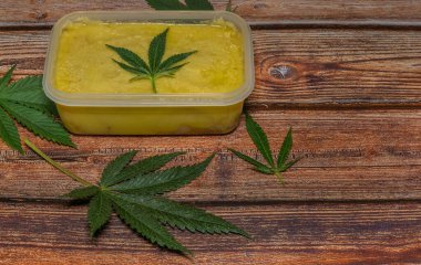 Ahşap masa üzerinde marihuana yağı zencefilli ekmek ve yeşil yapraklar.