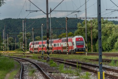 Kırmızı elektrikli lokomotifli yolcu treni ve yaz akşamları kırmızı yolcu vagonları.