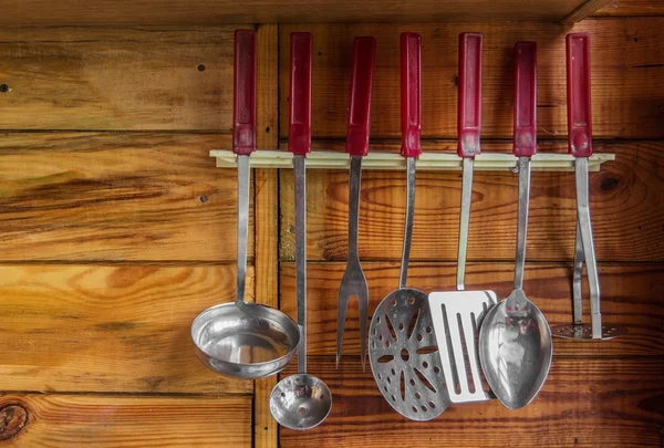 Utensilios de cocina en la pared sobre un fondo de madera — Foto de Stock