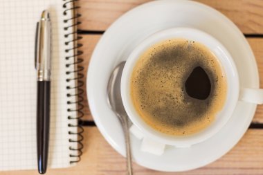 fincan kahve ve bir not defteri ile ahşap arka plan üzerinde kalem