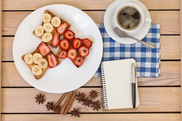 coffee and toast with strawberries and bananas on plate