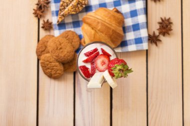 milkshake çilek ve yaban mersini, ahşap arka plan üzerinde pişmiş kruvasan ile