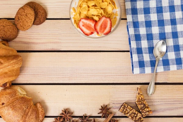 Mısır gevreği süt kruvasan ve ahşap arka plan günü kahvaltıda çilek ile