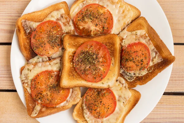 toast with cheese tomato basil oregano on a wooden background
