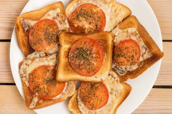 Toast med ost tomat basilika oregano på trä bakgrund Stockbild