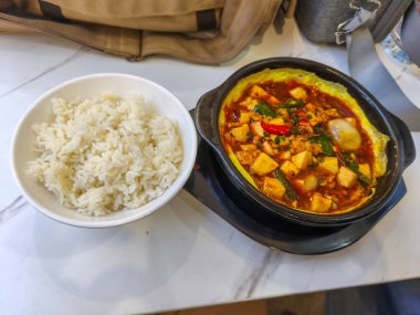 Spicy Mapo Tofu with rice, a classic Sichuan dish, served in a traditional clay pot.
