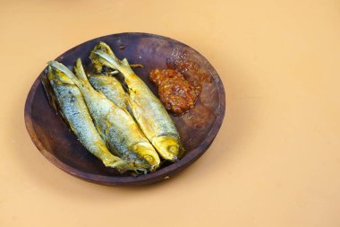 Geleneksel Endonezya mutfağından sambal ile kızartılmış süt balığı, ahşap bir tabakta servis edilir..