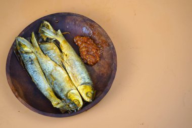 Geleneksel Endonezya mutfağından sambal ile kızartılmış süt balığı, ahşap bir tabakta servis edilir..