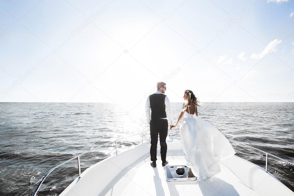 couple sailing on white yacht sunshine water glitters and shimme