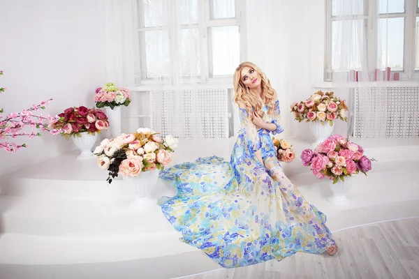 Hermosa chica modelo mujer retrato makiyad profesional y el pelo en un vestido de flores sobre un fondo floral, tono brillante, labios rosados, pelo rubio, rubio rizos de sonido alrededor  . — Foto de Stock