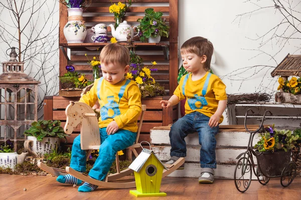 Παιδιά στο φόντο της άνοιξης διακόσμηση σε κίτρινα μπλουζάκια, λιβάδι λουλουδιών . — Φωτογραφία Αρχείου